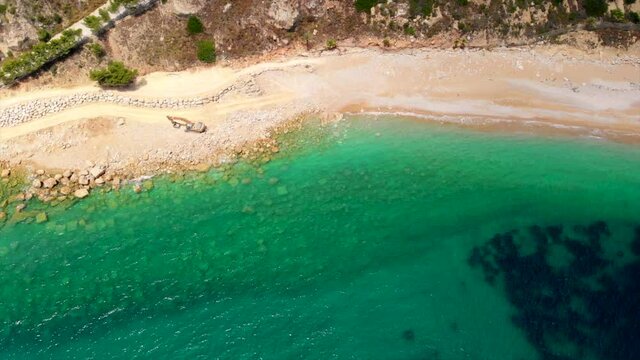 Cala del Moraig coastline from top. Beach closed for repairs by excavator machine. Aerial drone point of view turquoise green water, transparent lagoon water of Mediterranean Sea. Costa Blanca, Spain