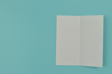Two folded blank paper leaflet on blue background.