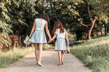 Mom and daughter in same outfit walking together down the road bare foot