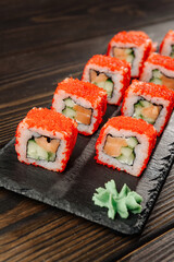 Rolls with fish and red caviar on a dish with wasabi.