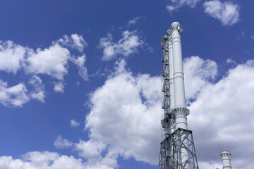 Obraz premium The observation tower on the blue background. Blue sky with clouds. Manufacture background. White tower on a blue background. Commercial texture. Factory view. 