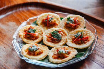 Crispy rice cake and pork and shrimp dipping in plate on wood table. thai food