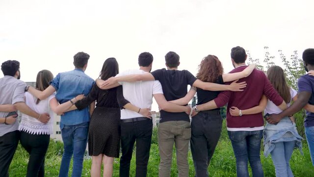Rear view of group of friends standing in a row in park