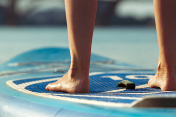 Close up legs. Young attractive woman standing on paddle board, SUP. Active life, sport, leisure...