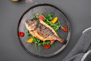 Hot grilled dorado fish with cherry tomatoes, arugula, lemon