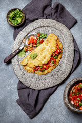 Big potato pancake with tomato sauce salsa on gray plate, gray background, top view