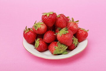 plato con montón de fresas y fondo liso color rosa