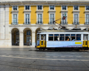 Naklejka na ściany i meble Vintage yellow tramway at the Commerce Square, in Lisbon, Portugal. Photography made using the panning technique.