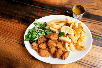 Home made scampi and chips served with mixed vegetables salad and lemon on top, English traditional...