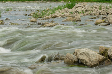 The flow of the river in the summer forest. Stones washed by water. Reflection on the water. water movement for a long exposure.