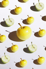 Golden and green apple minimalism pattern with hard shadow on the white background isolated. One big apple among little apples. Top view flat lay, copy space