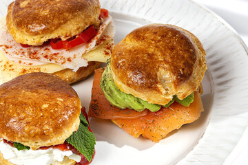 Assortment of homemade scones with ham, cheese, avocado, salmon, cream cheese and strawberry jam