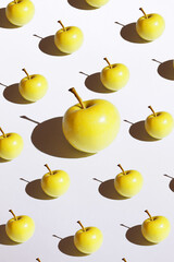 Golden apple minimalism pattern with hard shadow on the white background isolated. One big apple among little apples. Top view flat lay, copy space
