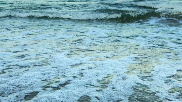 A close-up of smoothly walking into the waves while they crash on the shorе