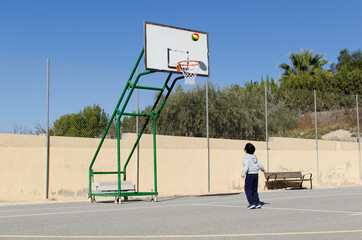 Niño lanzando a canasta en una pista al aire libre