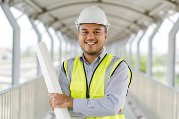 Portrait engineer handsome man or architect looking construction with blueprint and white safety  helme in construction site.