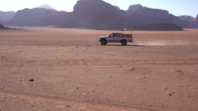 Wadi Rum - a local car crossing fast, in sandstone desert landscape
