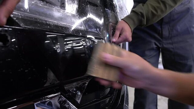 Close-up of applying a clear paint protection film to a car bumper.