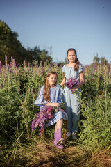 Fototapeta premium Happy two little sisters play outdoors in a summer park. Family lifestyle. Resting together on green grass