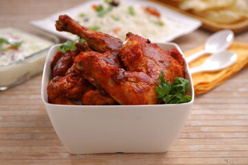 Fried chicken legs arranged in a white square bowl with ghee rice arranged in the background.selective focus