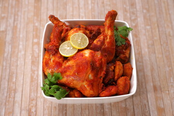 fried chicken legs arranged in square white bowl with wooden background