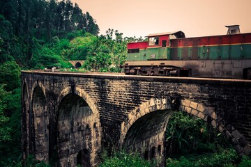 Old Train in motion over the world renowned nine arches bridge Demodara, Ella through beautiful lush green and tea estates towards the ella tunnel in the morning light