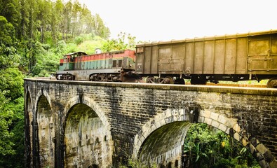 Freights Train in motion over the world renowned nine arches bridge demodara ella through beautiful lush green and tea estates towards the ella tunnel in the morning light