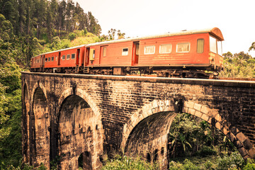 Vintage Train with observation car in motion over the world renowned nine arches bridge demodara, through beautiful lush green and tea estates towards the ella tunnel in the morning light