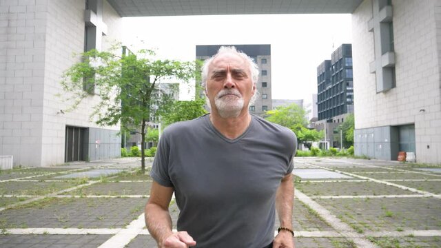 Slow motion shot of senior man jogging in city
