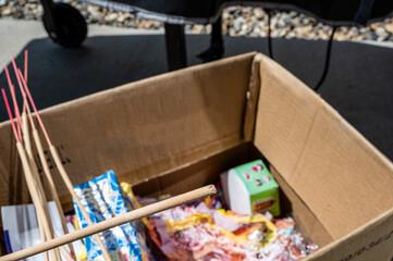 Lighter punk stick held in a hand over box of fireworks