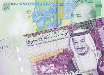 A close up image of a one Romanian leu bank note with a colorful five riyal Saudi Arabian bank note in macro