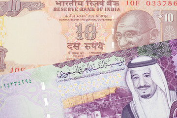 An orange, Indian ten rupee bill, close up with A colorful five riyal note from Saudi Arabia