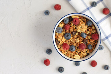 Muesli and oatmeal with nuts and fresh berries blueberries and raspberries on a light concrete background. Top view with space for text. Light Breakfast, proper nutrition.