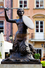 WARSAW, POLAND - OCTOBER 25, 2016: Mermaid with a sword and shield. In the background beautiful Tenement houses on the Old Market Square in Warsaw, the capital of Poland, Europe © Milosz Maslanka