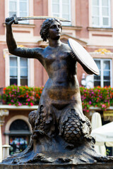 WARSAW, POLAND - OCTOBER 25, 2016: Mermaid with a sword and shield. In the background beautiful Tenement houses on the Old Market Square in Warsaw, the capital of Poland, Europe © Milosz Maslanka