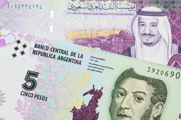 A five peso bill from Argentina, close up in macro with a colorful five riyal bank note from Saudi Arabia
