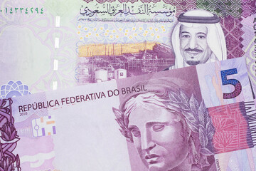 A five Saudi riyal bank note with a pink and purple five Brazilian reais bill.  Shot in macro.