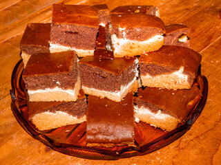 Three colored brownies with sweet cottage cheese in the middle, stacked into multiple layers on a glass platter