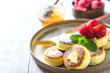 Cheesecakes with honey and raspberries. Traditional Russian sweet pancakes. Healthy breakfast. Homemade food