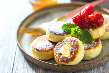 Cheesecakes with honey and raspberries. Traditional Russian sweet pancakes. Healthy breakfast. Homemade food