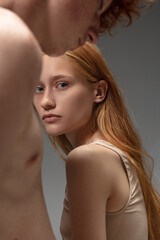 Art look. Fashion portrait of beautiful redhead couple isolated on grey studio background. Concept...