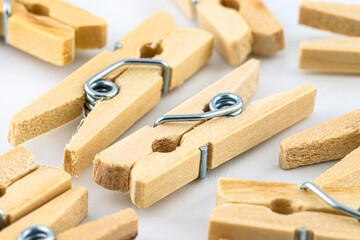 Macro shot of miniature, wooden clamps lying in a group on a white background.