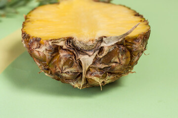 Half cut fresh pineapple on a pastel green background. Summer concept.