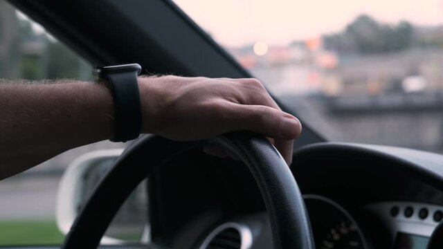 Close up male hand onb wheel with watch. Man drive car on road.