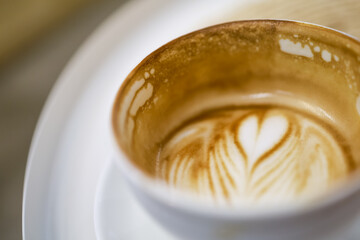 Close up of dirty empty of white cup of hot coffee latte with milk form art heart shape.