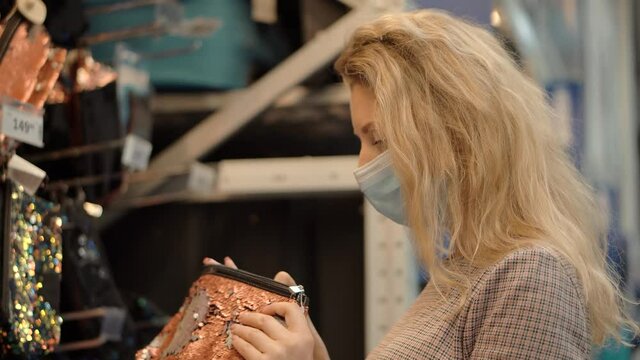 Woman Shopper Choosing Product In Hypermarket Store.Girl In Face Mask Shopping In Market On Covid19 Coronavirus Pandemic Quarantine Lock down. Bayer In Medical Mask In Supermarket Avoid Self Distance
