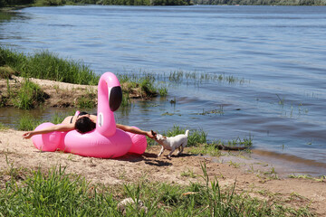 Rest on the banks of the Oka River. Girl on a pink air mattress and a dog