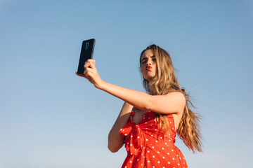 Beautifulgirl makes a selfie outdoors in a summer sunset