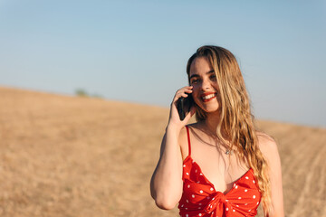 Beautiful blond girl at sunset in countryside speaks at phone
