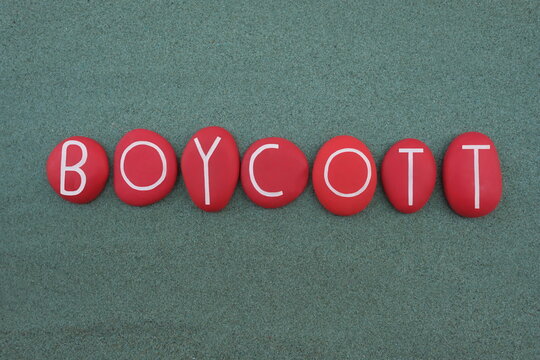 Boycott word composed with red colored stone letters over green sand